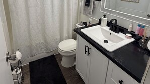 A bathroom with a white toilet, a black sink, and a shower curtain. - Soft Haven/ Warm and Cozy Getaway (Clarksville)