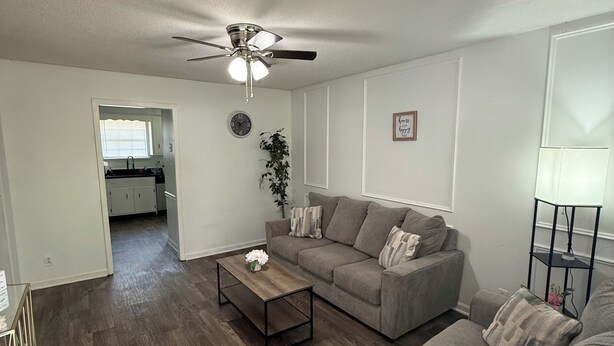 A living room with a grey sofa, a coffee table, and a ceiling fan. - Soft Haven/ Warm and Cozy Getaway (Clarksville)