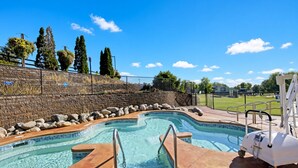 Una piscina con indicador de profundidad de 90 centímetros, rodeada por un muro de ladrillo, un césped y árboles.