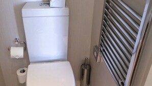 A compact bathroom with a white toilet, a paper towel holder, and a metal bidet. - wangwangwang (Kwun Tong)