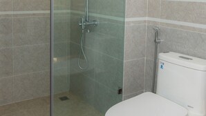 A bathroom with a glass-enclosed shower, a toilet, and tiled walls. - wangwangwang (Kwun Tong)