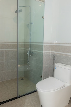 Un baño con cabina de ducha de vidrio, inodoro y paredes con azulejos.