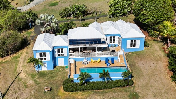 Ein großes, zweistöckiges Haus mit Swimmingpool, zahlreichen Fenstern und einer überdachten Terrasse.