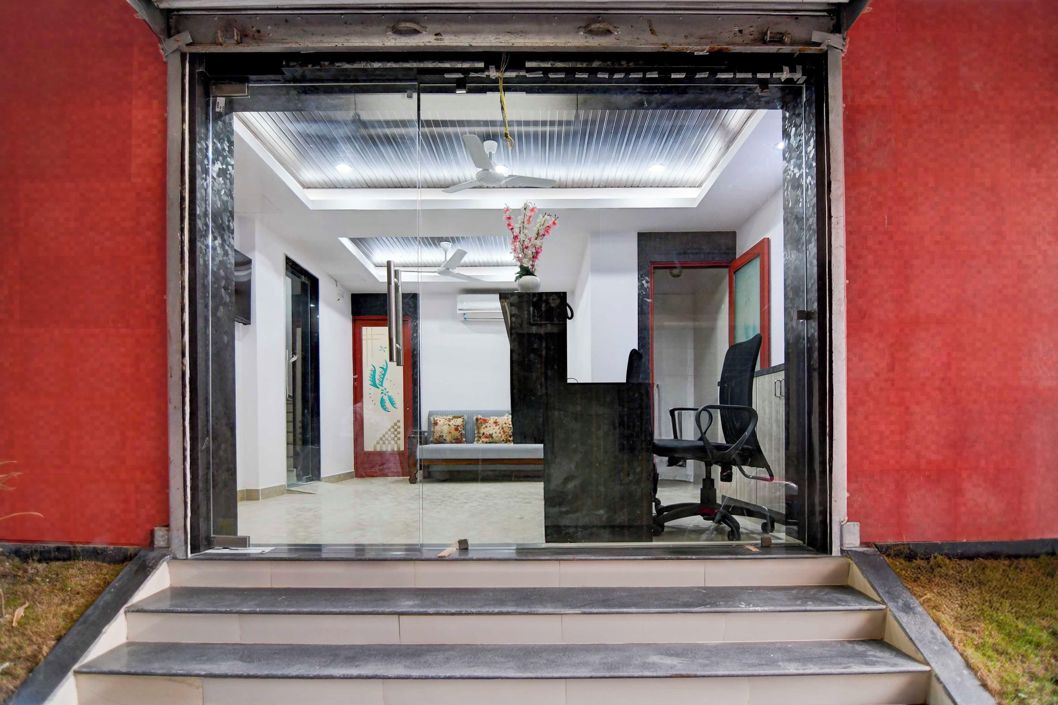 A modern office entrance with a glass door, a reception desk, and a staircase leading inside.