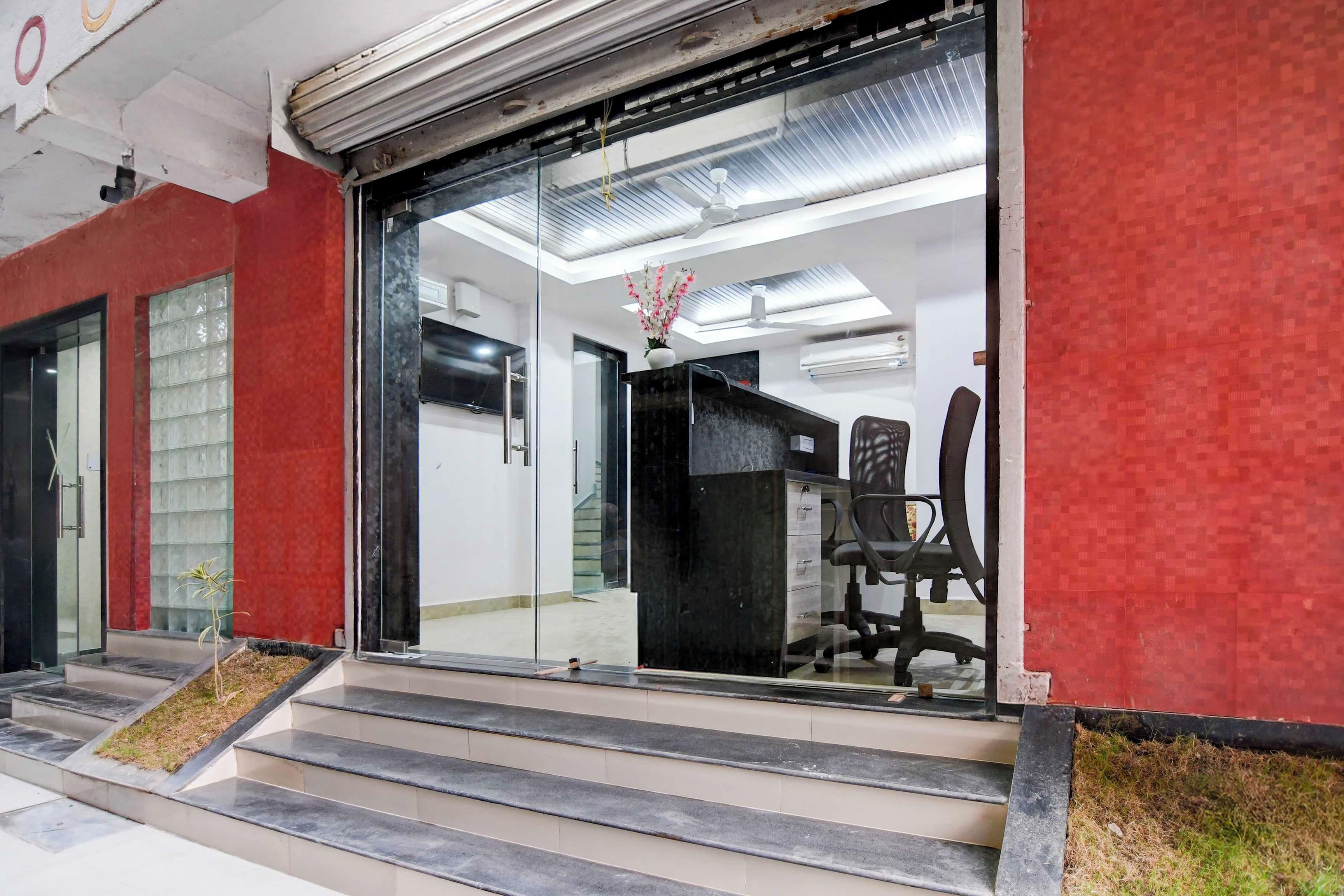 A modern office interior with a reception desk, office chairs, and a staircase leading to the entrance.