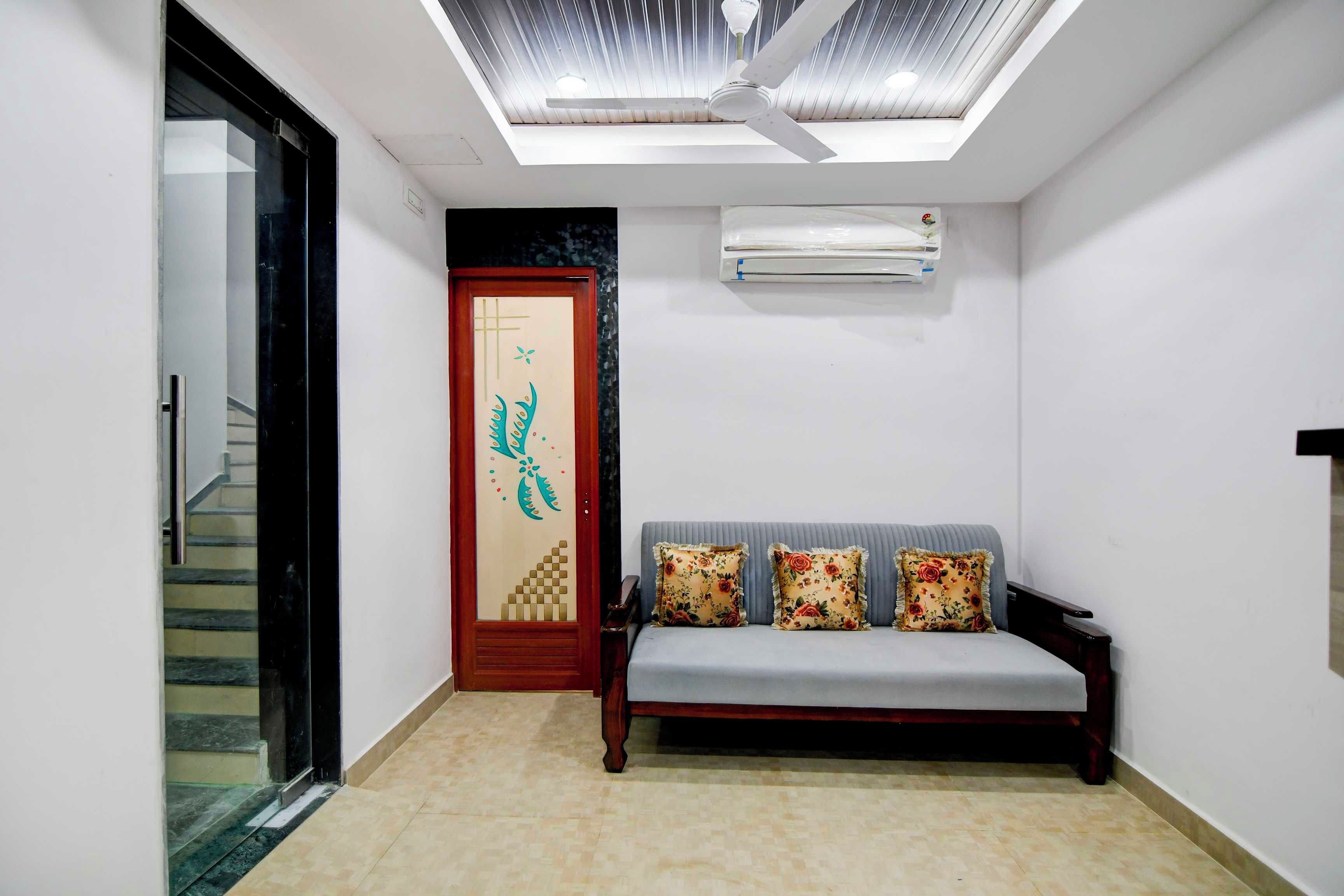 Una sala de estar moderna con un sofá, una puerta decorativa, un ventilador de techo y un equipo de aire acondicionado.