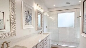 A modern bathroom with a large mirror, two sinks, and a walk-in shower. - NEW: Saltwater Sky - Rooftop deck and private pool (Eastpoint)