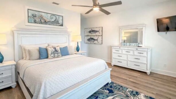 A bedroom with a bed, nightstands, a dresser, a ceiling fan, and artwork on the walls. - NEW: Saltwater Sky - Rooftop deck and private pool (Eastpoint)