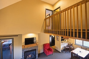 A multi-level living space with a fireplace, a television, and a dining area with chairs and a table.