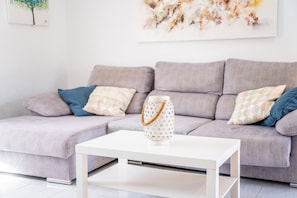 Ein modernes Wohnzimmer mit einem grauen Sofa, einem weißen Couchtisch und einer dekorativen weißen Laterne.