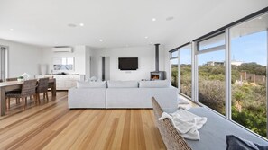 A modern living room with a sofa, dining area, and a fireplace. - Saltaire - stunning 4 bedroom property with indoor pool (St Andrews Beach)