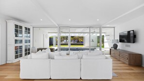 A modern living room with a sectional sofa, a television, and a bookshelf. - Saltaire - stunning 4 bedroom property with indoor pool (St Andrews Beach)
