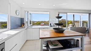 A modern kitchen with a wooden island, a sink, and a view of the outdoors. - Saltaire - stunning 4 bedroom property with indoor pool (St Andrews Beach)