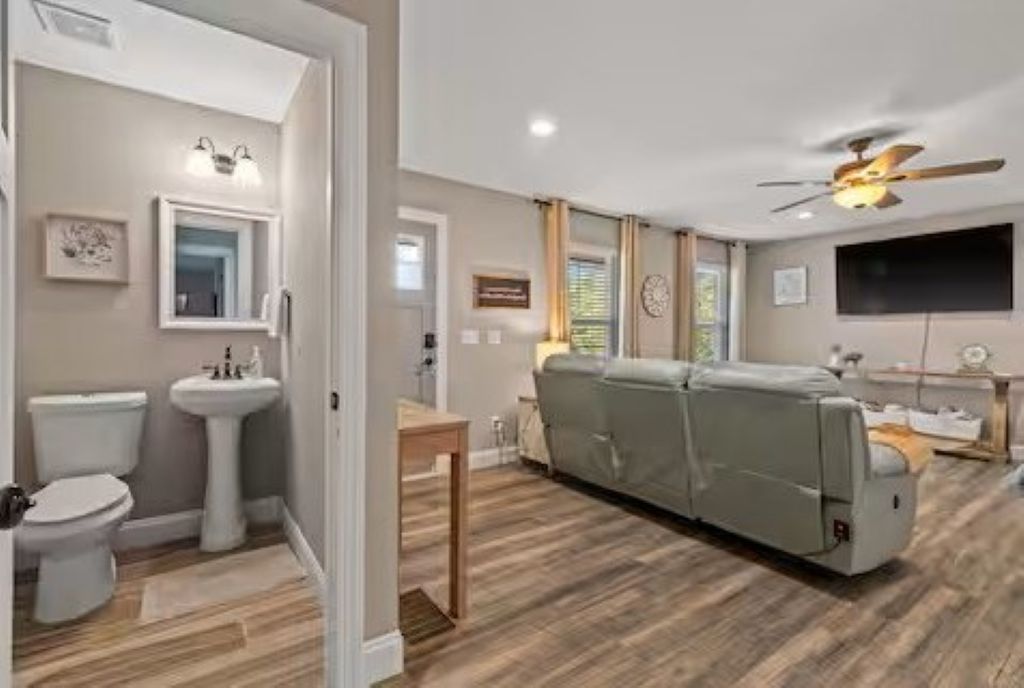 Una sala de estar moderna con un sofá, televisor y ventilador de techo.