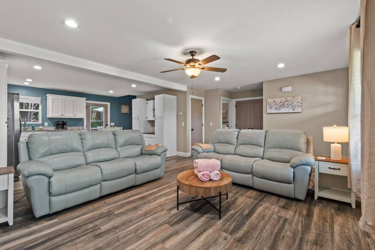 A living room with two grey sofas, a wooden coffee table, and a ceiling fan.