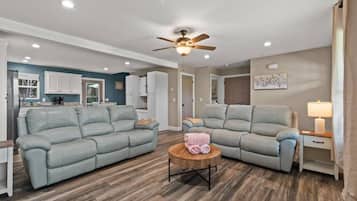 A living room with two grey sofas, a wooden coffee table, and a ceiling fan.