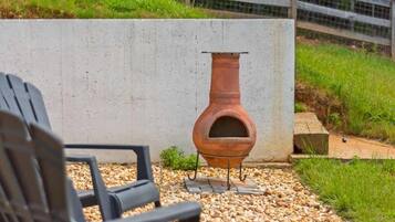 A rustic outdoor seating area with a concrete wall, a metal fire pit, and a gravel path.