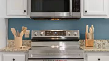 A kitchen with a stainless steel microwave, oven, and a set of knives on the counter.