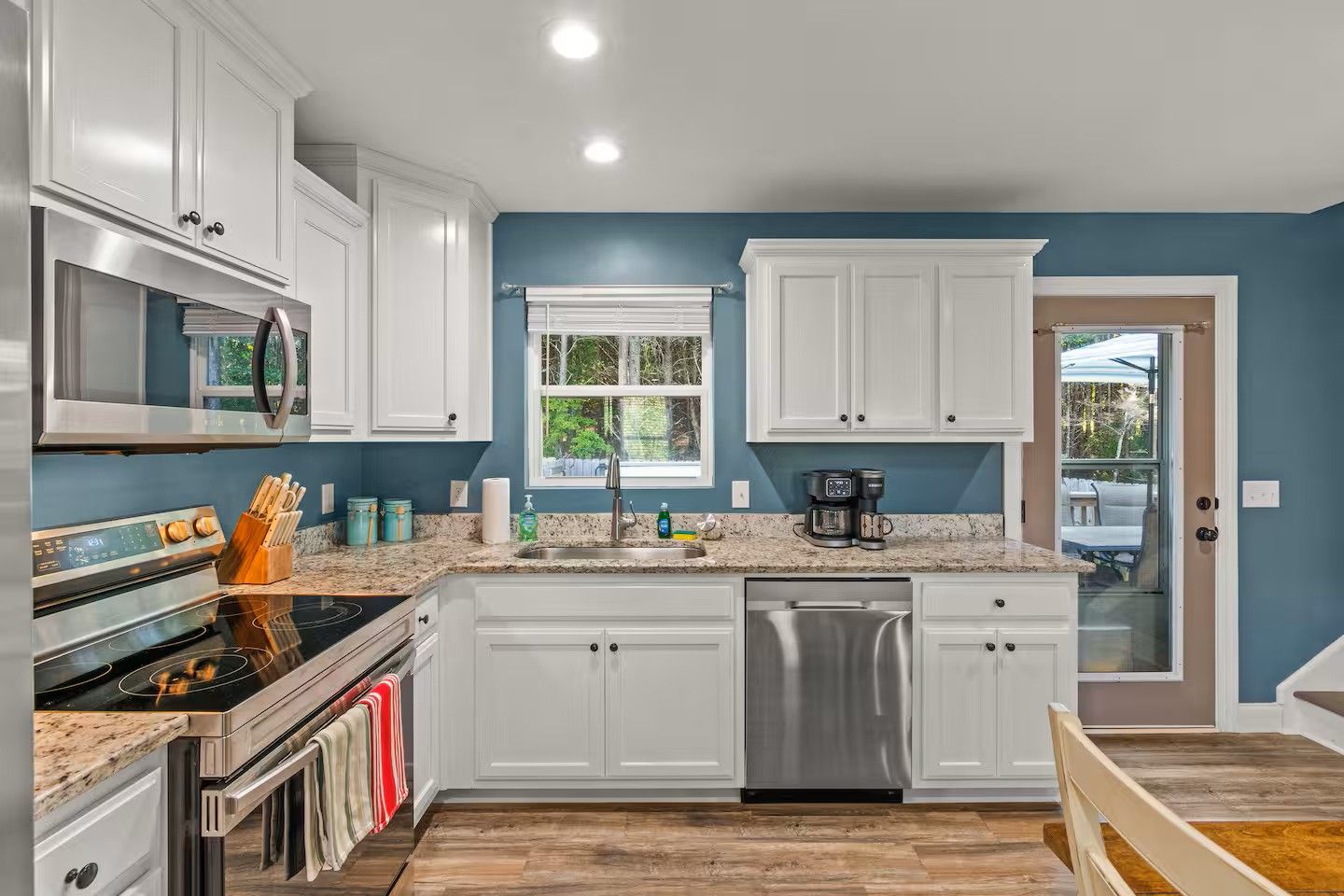 A modern kitchen with white cabinets, stainless steel appliances, and a blue accent wall.