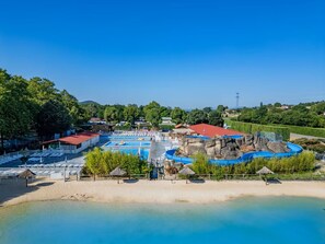 Ein Resort mit Schwimmbad, Strandabschnitt und einer Felsformation.