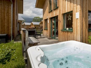 Une cabane en bois dotée d’un bain à remous, d’un espace extérieur aménagé et offrant une vue sur les autres cabanes.