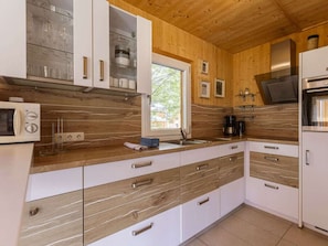 Eine moderne Küche mit Holzschränken, einem eingebauten Backofen und einem Fenster für natürliches Licht.