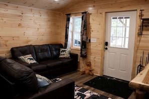 A wooden interior with a sofa, a teddy bear, and a door.