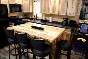 A kitchen with a central island, bar stools, a microwave, and a coffee machine.
