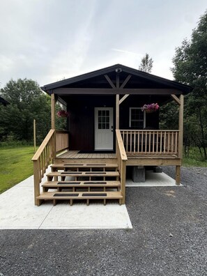 A small wooden cabin with a porch, a door, and a window.