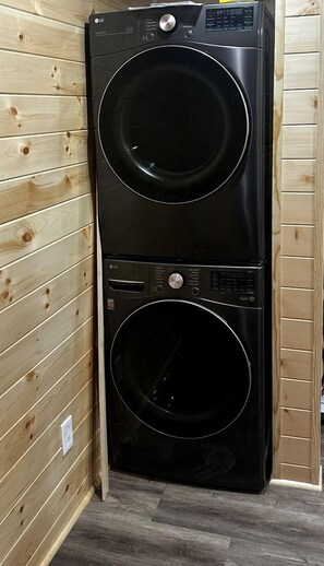 A black LG front-loading washer and dryer unit in a wooden-paneled room.