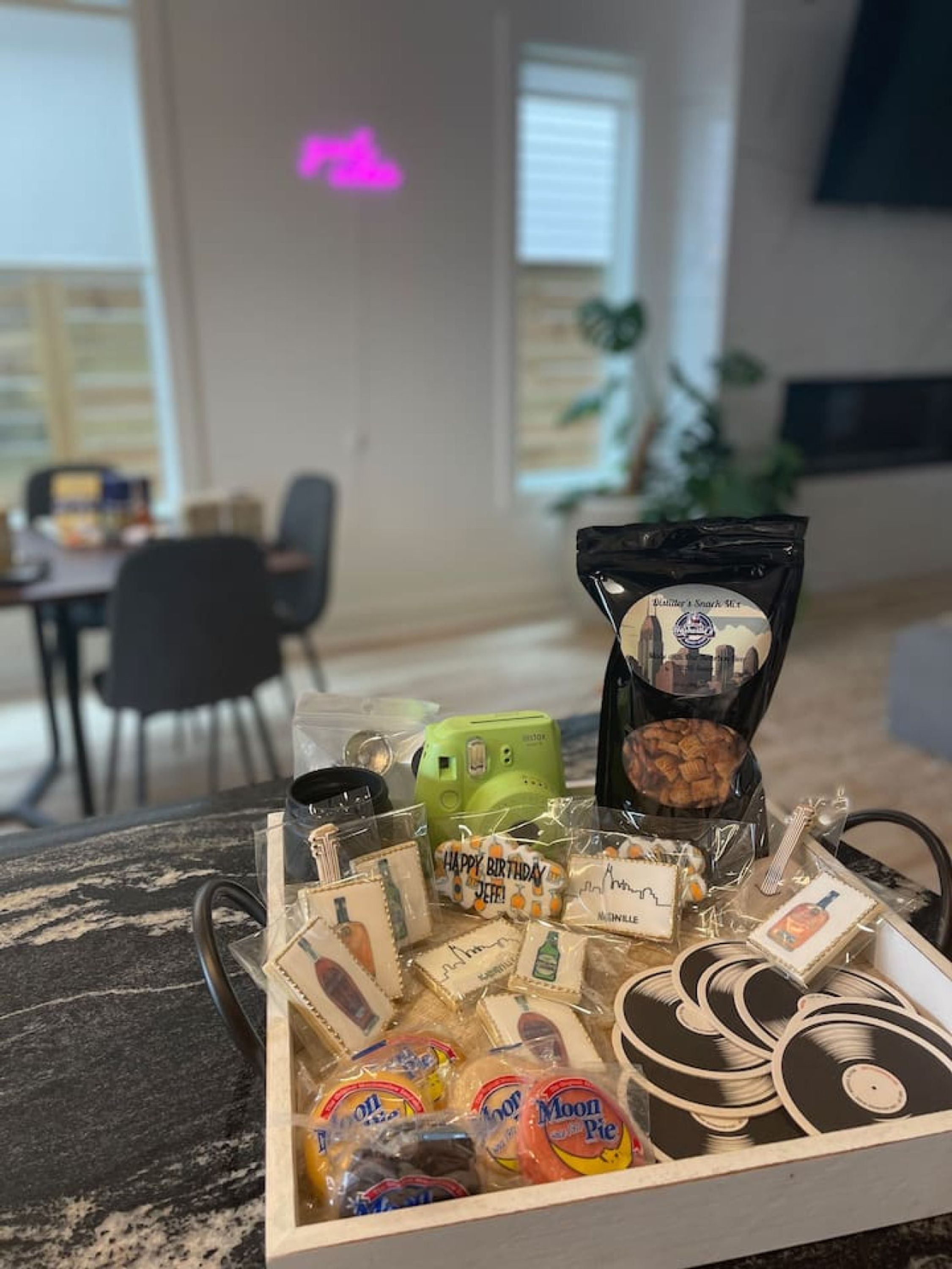 Ein Tablett mit verschiedenen Gegenständen, darunter eine Tüte Moon Pie, eine grüne Kaffeemaschine und mehrere kleine Geschenkboxen.