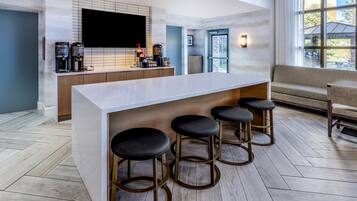 A modern kitchen with a large island, bar stools, and a flat-screen TV.