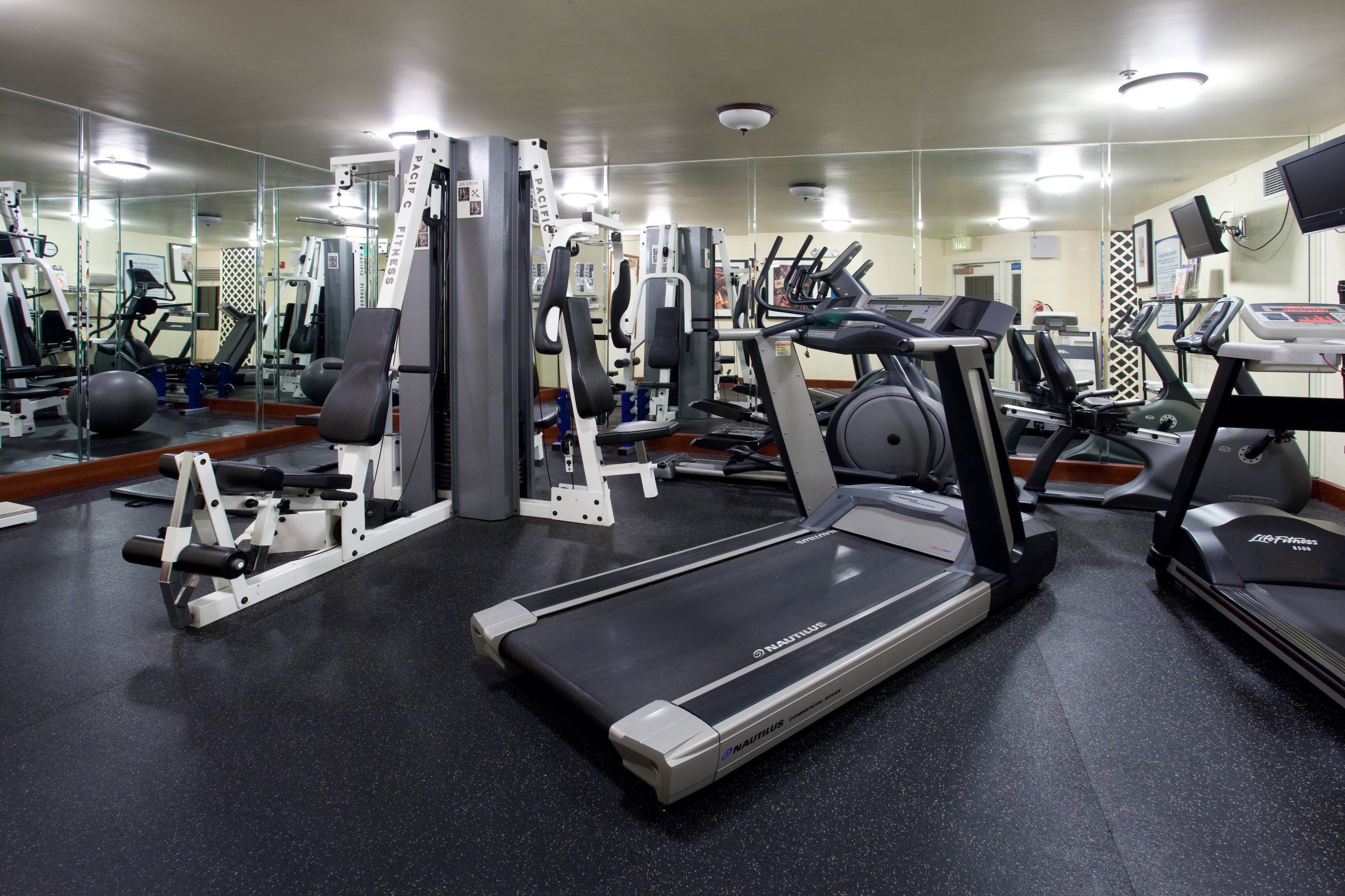 Een sportschool met loopbanden, krachtapparaten en fitnessballen.