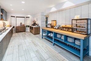 Cozinha moderna com bancada de madeira, prateleiras azuis e uma vitrine com doces.