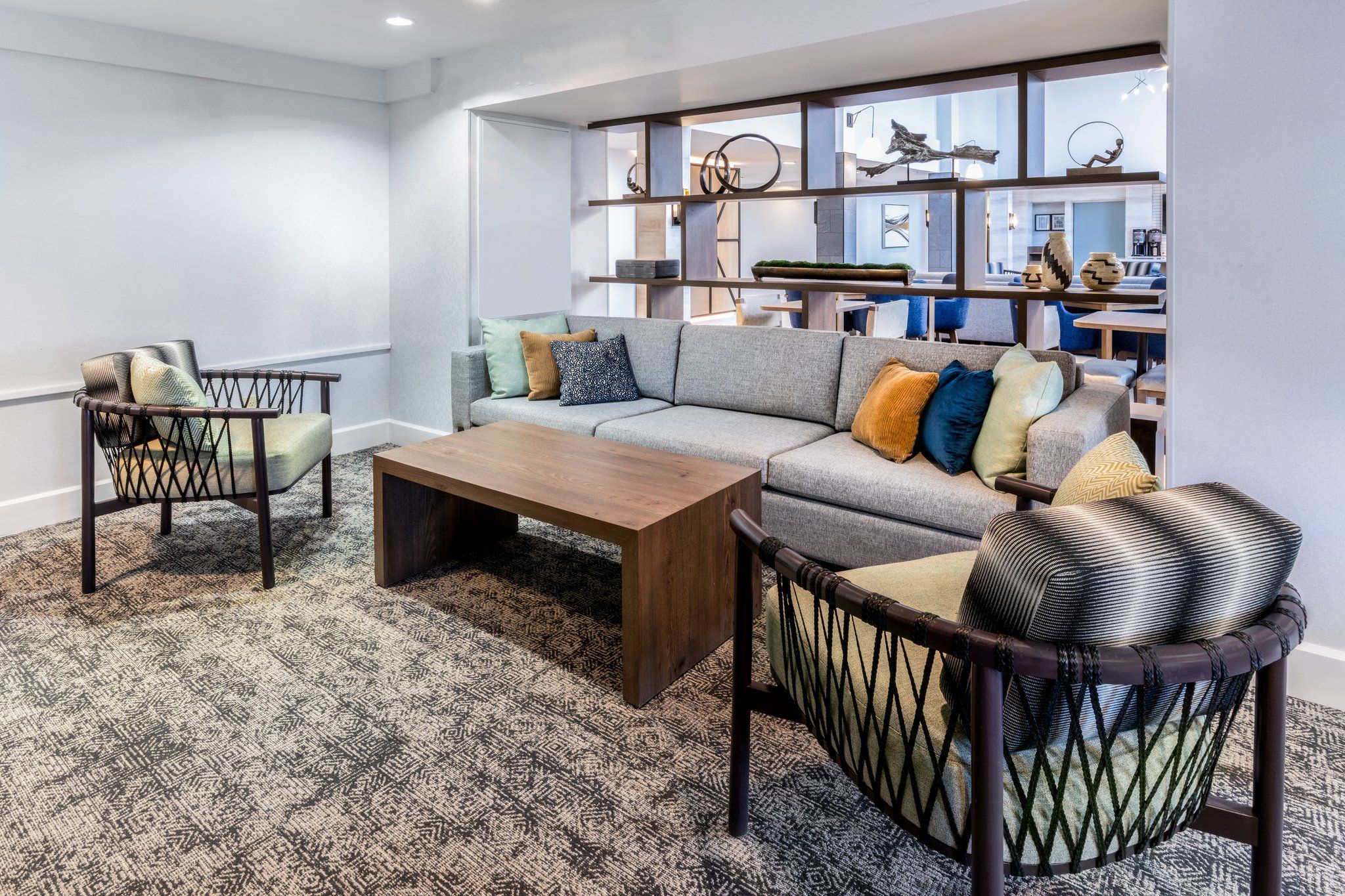 A modern living room with a sofa, armchairs, a coffee table, and a patterned carpet.