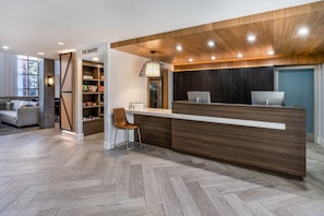 A modern reception area with a wooden reception desk, a laptop, and a sign reading 'THE PANTRY.'