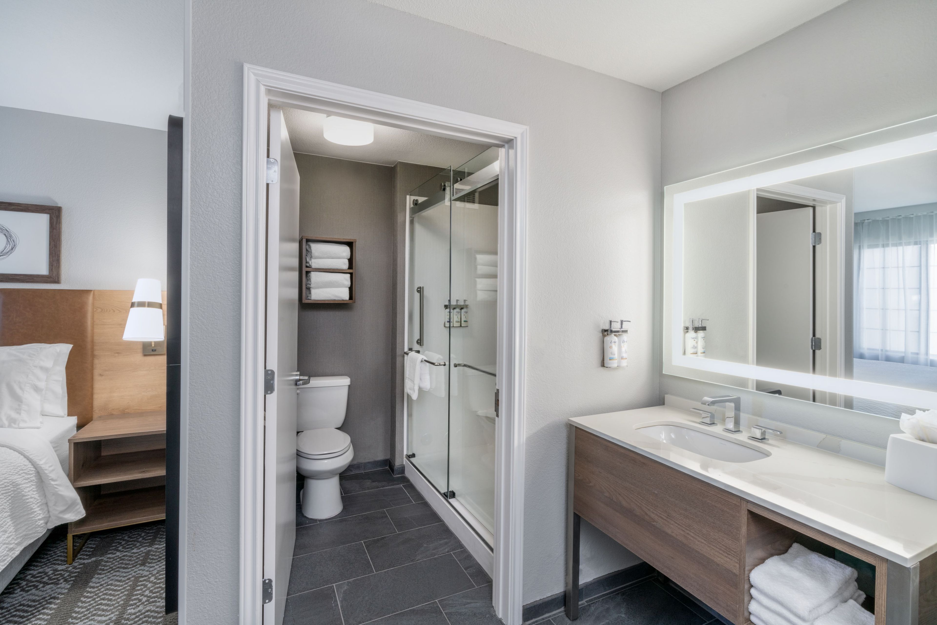 Un baño de hotel con ducha, inodoro y un espejo grande.