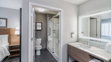 Un baño de hotel con ducha, inodoro y un espejo grande.