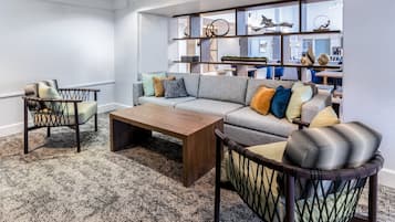 A modern living room with a sofa, armchairs, a coffee table, and a patterned carpet.