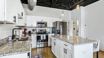A modern kitchen with white cabinetry, stainless steel appliances, and a granite countertop.