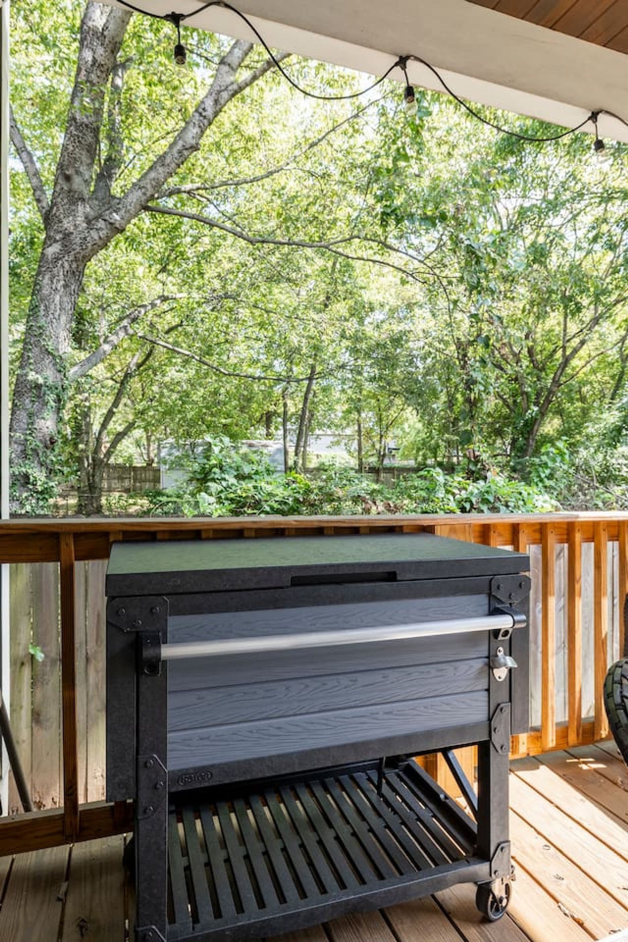 Ein Grill auf einer Holzterrasse mit Blick auf einen Wald.