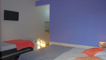 Un dormitorio con dos camas, un televisor en la pared y un baño visible a través de una puerta abierta.