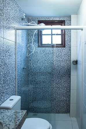 A bathroom with a shower enclosure, a toilet, and a window. - Pousada Prisco Peró (Cabo Frio)