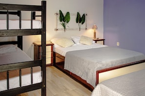 A room with a bunk bed, a single bed, a nightstand, a lamp, and a wall-mounted plant. - Pousada Prisco Peró (Cabo Frio)