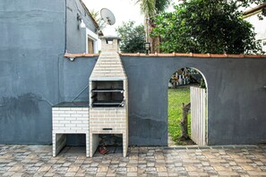 A brick-built outdoor grill with a chimney, a satellite dish, and a small archway leading to a garden. - Pousada Prisco Peró (Cabo Frio)