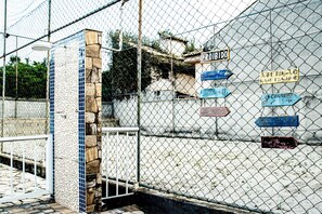 A chain-link fence with multiple directional signs attached to it. - Pousada Prisco Peró (Cabo Frio)