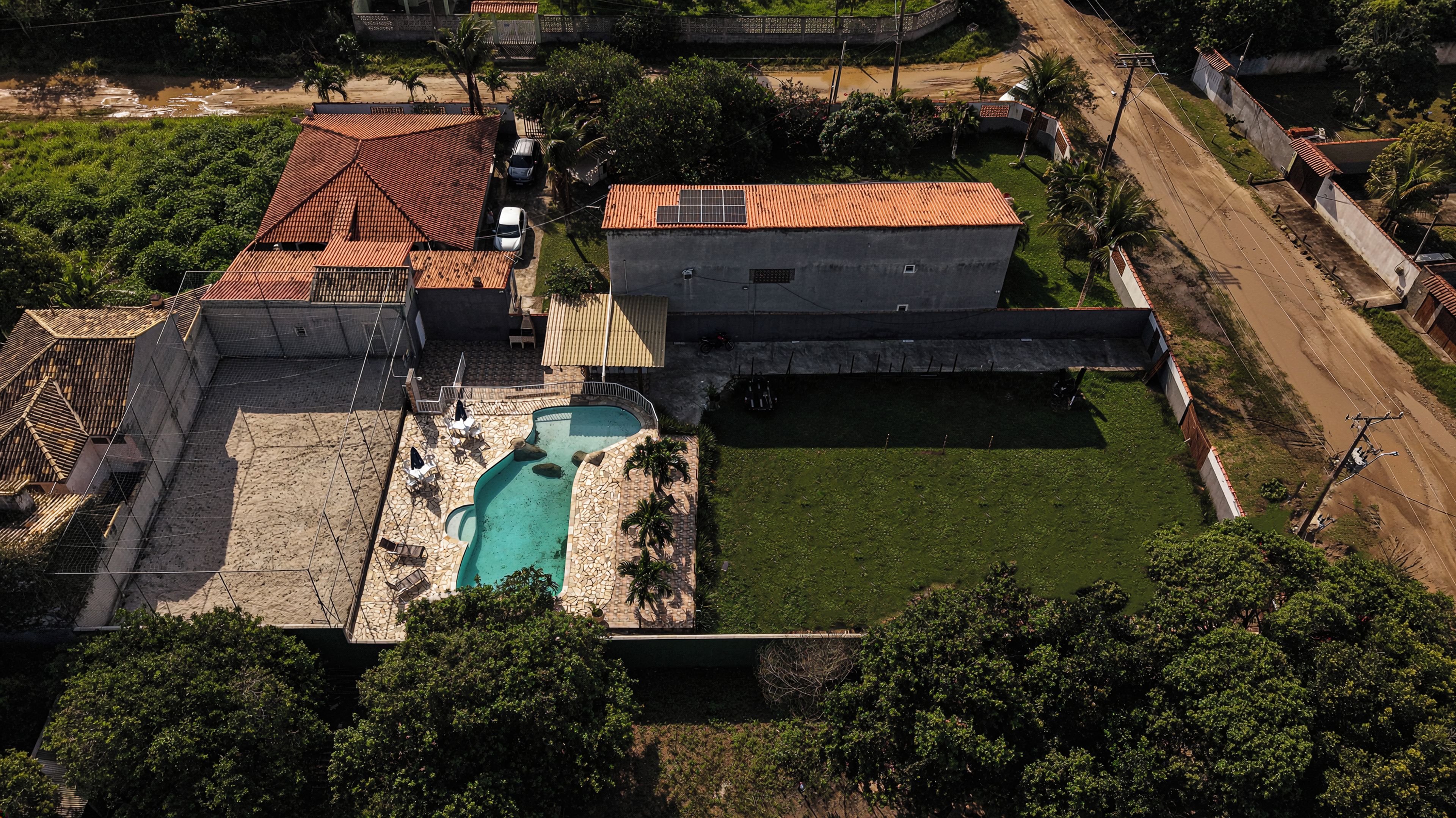 Vista aérea de una zona residencial con piscina, patio cercado y una calle.