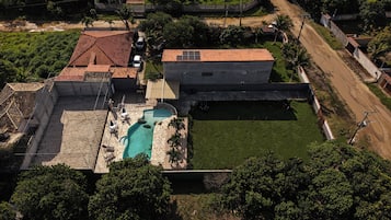 Vista aérea de una zona residencial con piscina, patio cercado y una calle.