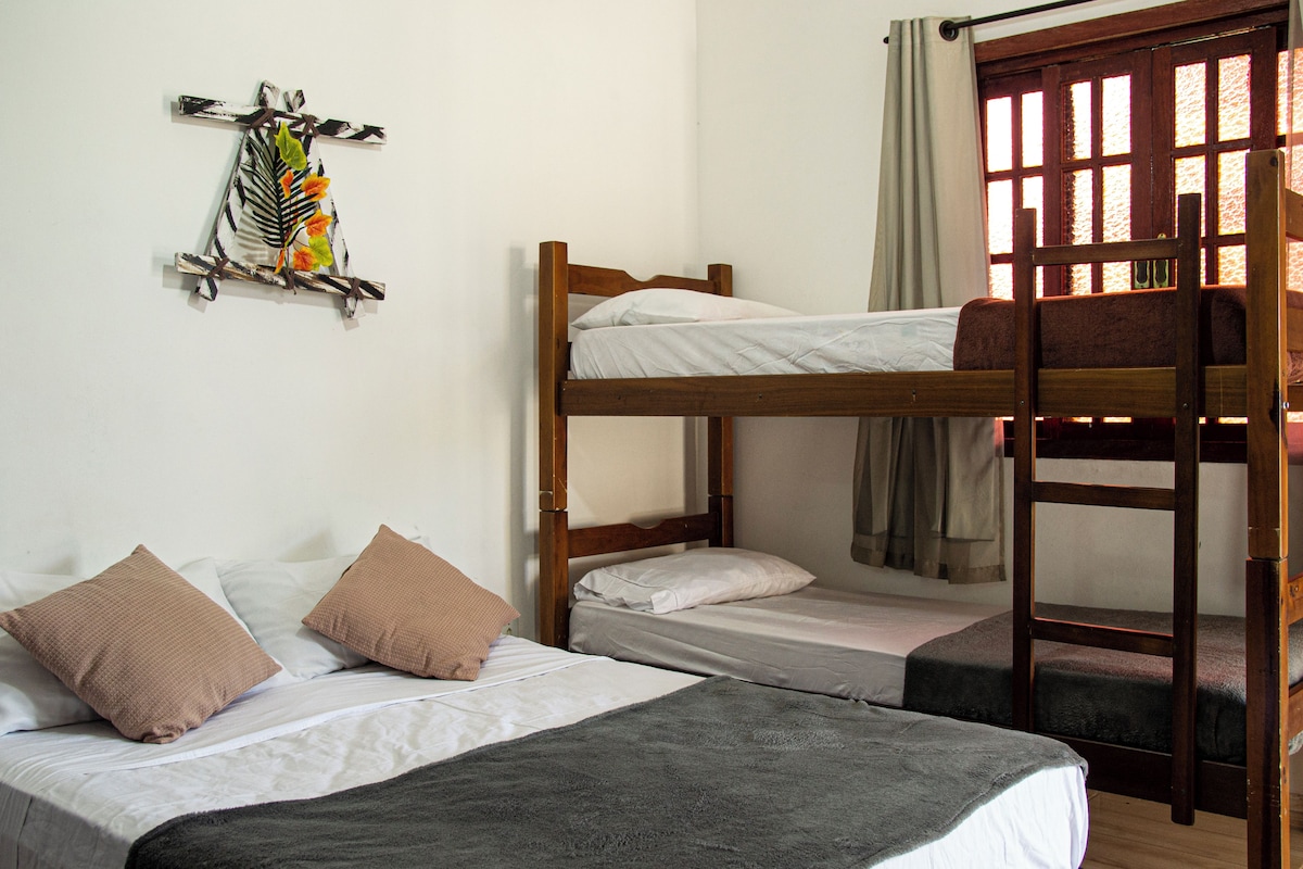 A bunk bed room with a wooden headboard, two pillows, a blanket, and a wall decoration.