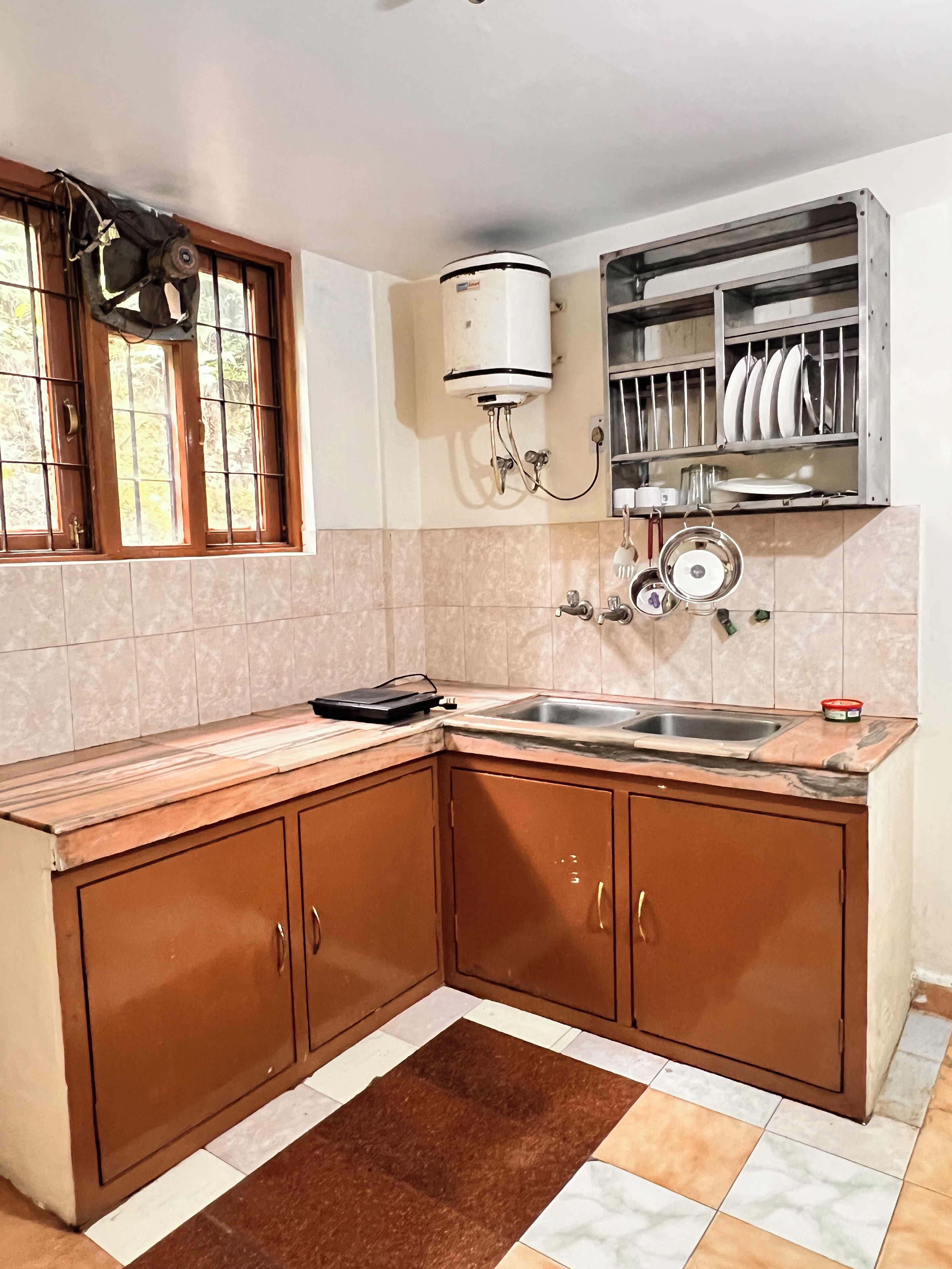 A kitchen with a sink, cabinets, a stove, and a dish rack.